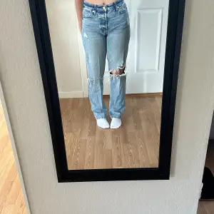 Säljer ett par ljusa jeans med coola slitningar på knäna. De har en hög midja och en straight passform som ger en avslappnad look. Perfekta för en casual outfit! 🕶️