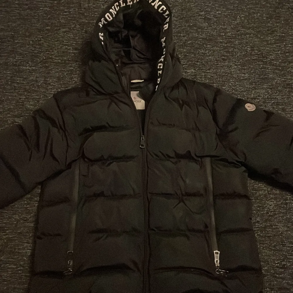 Säljer en snygg svart pufferjacka från Moncler. Jackan har en stor huva med Moncler-logga och dragkedja framtill. Perfekt för kalla vinterdagar!. Jackor.