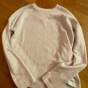 Beige tröja från Gina Tricot - Mysig beige tröja från Gina Tricot i storlek M. Perfekt för kyliga dagar med sin mjuka polyesterblandning. Tröjan har en enkel design med långa ärmar och rund halsringning. Passar både till vardags och mysiga hemmakvällar.