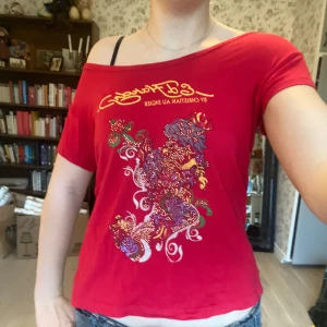 Röd Ed Hardy tröja - En riktigt fin Ed Hardy t-shirt som tyvärr inte kommer till användning längre. Det står storlek L men den sitter verkligen bra på mig som brukar ha XS-M på toppar.  Det går att bära den off shoulder eller som vanligt, lite stretchigt material.