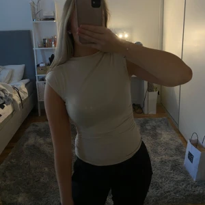 Beige topp med rynkdetaljer - Säljer en snygg beige topp i tight passform. Den har korta ärmar och coola rynkdetaljer på sidorna. Perfekt för både vardag och fest! 🥳Storlek xs. Sällan använd så fint skick! 💓💓