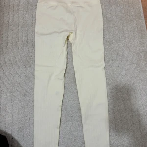 Beige ribbade leggings från New Apparel - Säljer ett par snygga gula ribbade leggings från New Apparel i storlek M (passar S). Köpta från Ullared. 💛(ej använda)