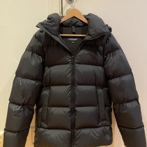 Svart vinterjacka från J. Lindeberg - Säljer en svart dunjacka från J. Lindeberg i mycket bra skick. Jackan köptes förra vintern men har knappt använts så den har inga defekter eller liknande. Jackan är i storlek S. Nypriset ligger på 4800kr.