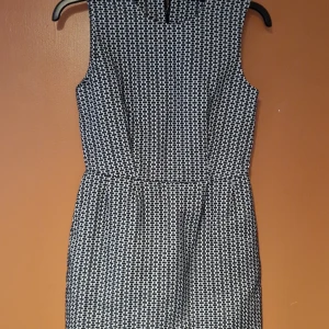 Mönstrad klänning från COS - Snygg och stilren klänning från COS i storlek 36. Den har ett svartvitt mönster och är ärmlös med en dragkedja i ryggen. Perfekt för både vardag och festliga tillfällen. Klänningen har en normal passform och är gjord i ett bekvämt material.