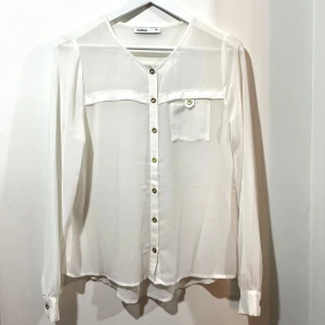 Vit blus - Vit tunn blus med guldknappar.