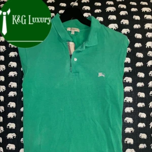 Grön pikétröja från Burberry - Säljer en snygg grön pikétröja från Burberry. Den har en klassisk krage och knappar framtill. Perfekt för en avslappnad men stilren look. Passar både till vardags och lite finare tillfällen. Bra skick! Passar dig som 175-185