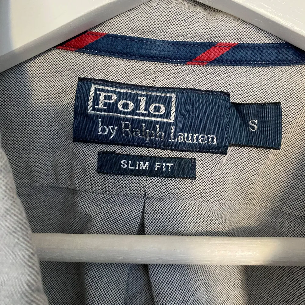 Säljer en stilren grå skjorta från Polo Ralph Lauren i slim fit. Skjortan har långa ärmar och knappar framtill. Perfekt för både vardag och festliga tillfällen. Den är i mycket bra skick och har en liten broderad logga på bröstet.. Skjortor.