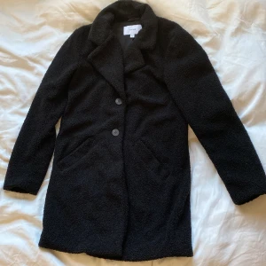 Kappa från Vila - Svart kappa i teddymaterial från Vila i stl 36. Säljes då den tyvärr är för stor för mig. Endast använd 1 gång.