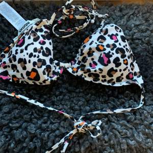 Säljer en superfin leopardmönstrad bikini från Moschino i nytt skick. Den har knytband både i nacken och ryggen för perfekt passform. Färgerna är en mix av svart, vit, rosa och orange som verkligen poppar! Perfekt för sommarens strandhäng eller poolpartyn. 🐆🌞