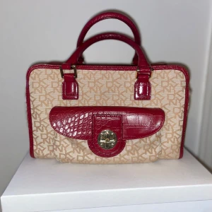 Vintage väska DKNY - Vintage DKNY Handväska I klassiskt monogramtryck med röda detaljer och gulddetaljer.