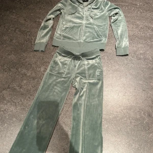 Grön  hoodie och byxor från Juicy Couture - Säljer ett supermysigt set  från Juicy Couture. Tröjan är S och byxorna är XXS. Hoodien har dragkedja och fickor framtill, medan byxorna har en bekväm resårmidja med knytband. Setet är i mycket bra skick.