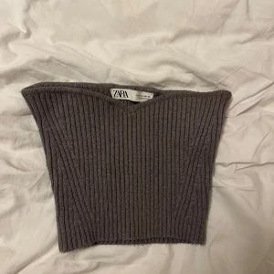 Grå ribbad tubtopp från Zara - Säljer en snygg grå ribbad tubtopp från Zara i storlek S. Perfekt för både vardag och fest! Toppen är i ett mjukt och stretchigt material som sitter bekvämt. Passar utmärkt till både jeans och kjol. 🖤