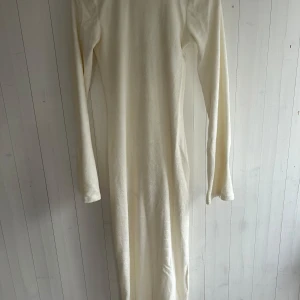 Vit långklänning med öppen rygg - Elegant vit långklänning med långärmad design och en vacker öppen rygg. Perfekt för festliga tillfällen eller en stilren sommarlook. Klänningen har en smickrande passform och är tillverkad i ett mjukt material som ger en bekväm känsla.