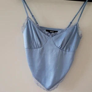 Ljusblå satinlinne från Bik Bok - Säljer ett superfint ljusblått satinlinne från Bik Bok i storlek XS. Linnet har tunna axelband och vacker spetsdetalj längs kanterna. Dragkjedja i midjan. Använd endast 1 gång så det är i mycket bra skick. Storlek: XS  Skickas inslagen i silkespapper i vattentätt paket.   Skicka pm för fler bilder. 