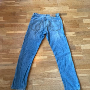 Blå jeans från Jack & Jones - Säljer ett par snygga blå jeans från Jack & Jones i modellen Loose/Chris. De har en klassisk femficksdesign och är i bra skick. Perfekta för en avslappnad stil och passar till de flesta tillfällen. Sköna och slitstarka, dessa jeans är ett måste i garderoben! Dessa är inte strykta för tillfället men det genomförs innan försäljning!🙌🏻