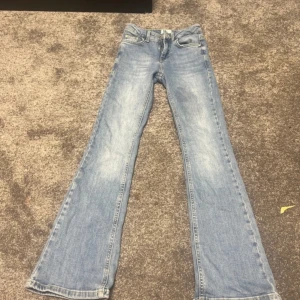 Blå jeans från Grunt - Säljer ett par snygga blå jeans från Grunt i modellen 'Texel Low Flare'. De har en låg midja och en bootcut-stil som ger en retro känsla. Perfekta för både vardag och fest! De är i bra skick och har en cool vintage-look.