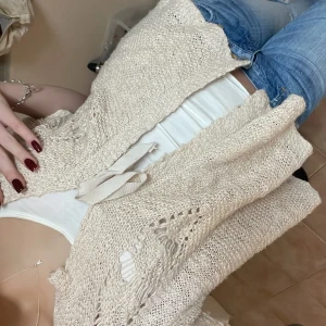 Beige stickad väst med knyt - Säljer en superfin beige stickad väst med knyt framtill. Den har ett snyggt hålmönster och är perfekt för lager-på-lager-stil. Passar bra till både jeans och kjol. Perfekt för vår och sommar! Storlek L men passar mig som brukar bära xs,s säljer för 250❤️