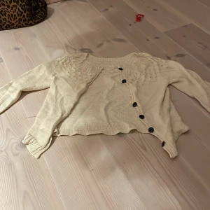 Beige kofta med knappar - Mysig beige kofta med fina detaljer och knappar framtill. Perfekt för kyliga dagar och att ha över en topp. Den har långa ärmar och en skön passform. Passar bra till både vardag och lite finare tillfällen.