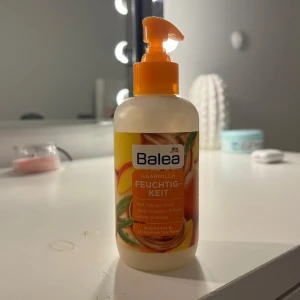 Balea fuktighetskräm med mangodoft - En återfuktande hårlotion från Balea med en härlig doft av mango. Den kommer i en praktisk pumpflaska som gör det enkelt att dosera rätt mängd. Perfekt för daglig användning för att hålla håret mjukt och återfuktat.