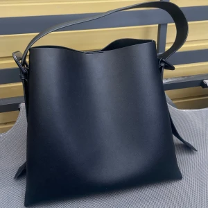 Mango axelväska - Snygg svart axelväska i skinn med enkel och stilren design. Perfekt för vardagsbruk eller en kväll ute. Väskan har en bred axelrem och är rymlig nog för alla dina nödvändigheter. Några på slitage, men fortfarande i bra skick.