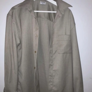 Beige skjorta från Filippa K - Säljer en stilren beige skjorta från Filippa K i storlek M. Skjortan har en klassisk krage och knappar framtill. Perfekt för både vardag och festliga tillfällen. Materialet känns mjukt och bekvämt mot huden. Passar bra till både jeans och kostymbyxor.