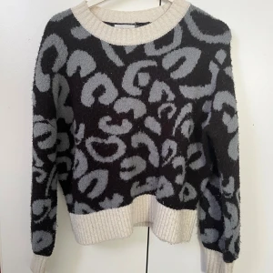 Mönstrad tröja från Grunt - Säljer en supercool tröja från Grunt i storlek M. Den har ett grått och svart leopardmönster som verkligen sticker ut. Tröjan är långärmad och har ribbade kanter vid hals, ärmslut och nederkant. Perfekt för höst och vinter! Storlek M, men mindre i storleken.