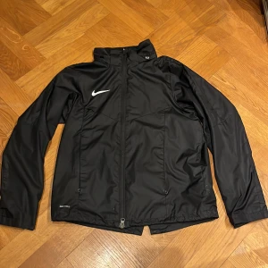 Svart Nike jacka  - Säljer en svart jacka från Nike i bra skick. Passar både till träning och vardagsbruk. Säljer den då jag inte använder den så mycket. Han tyvärr ett liten hål under nike märket men syns knappt