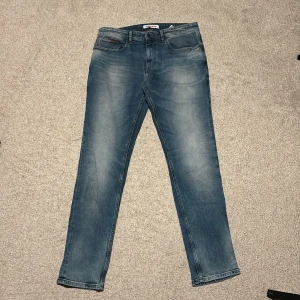 Tommy Hilfiger Jeans Blåa - Säljer ett par snygga blå jeans från Tommy Jeans i fint skick. Storleken är 32/32. Pris kan diskuteras. Skulle säga att dem är ”regular fit”. 