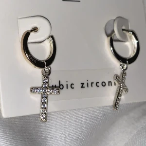 Örhängen kors med diamanter 925 silver  - Fick de i present men då jag föredrar guld läljs de nu. Örhängena är helt nya och aldrig använda! Helt nya örhängen med små diamanter i 925 äkta silver. Diamanterna är inte äkta. 