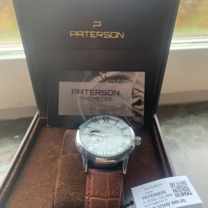 Paterson herrklocka med brunt läderarmband - Säljer en elegant Paterson herrklocka med ett stilrent silverfärgat urverk och romerska siffror. Klockan har ett brunt läderarmband som ger en klassisk look. Perfekt för både vardag och fest. Kommer i originalförpackning. 