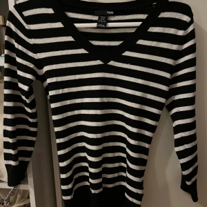 Svart och vit randig tröja från H&M - Säljer en snygg tajt svart och vit randig tröja från H&M. Den har en v-ringad hals och trekvartsärmar, perfekt för både vår och höst. Tröjan är i mycket bra skick och passar till både jeans och kjol!🖤🖤