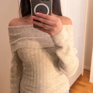 Beige offshoulder tröja - Säljer en superfin beige offshoulder tröja i ribbat material. Perfekt för både höst och vår, med långa ärmar som håller dig varm och stilren. Tröjan har en tight passform som framhäver figuren. Passar perfekt till jeans eller kjol för en chic look!