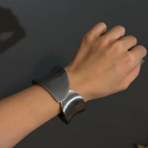 Elegant silverfärgat armband - Snyggt och modernt armband i silverfärg med en unik, böljande design. Perfekt för att ge en stilren touch till vilken outfit som helst. Passar både till vardags och festliga tillfällen.