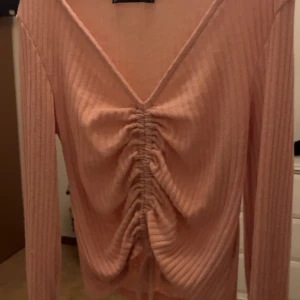 Rosa ribbad topp från FB Sister - Säljer en superfin rosa ribbad topp från FB Sister i storlek XS. Den har en snygg v-ringning och cool snörning framtill som ger en unik look. Perfekt för både vardag och fest! 💖