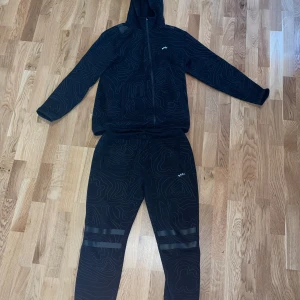 Svart träningsset från BOSS - Säljer ett svart träningsset från BOSS med coola mönster. Setet består av en hoodie med dragkedja och matchande byxor. Perfekt för träning eller en avslappnad dag. Materialet känns mjukt och bekvämt. Passar bra för höst och vår.         Nypris:4000