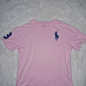 Rosa t-shirt från Polo Ralph Lauren - Säljer en snygg rosa t-shirt från Polo Ralph Lauren. Den är använd ett fåtal gånger. Storleken är 152 men passar 162 och XXS