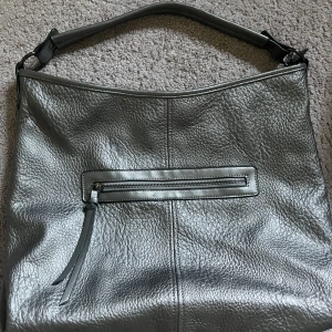 Vintage väska  - En silvrig vintage väska, säljer då den inte kommer till användning, den är väldigt rymlig och perfekt till skolan. 