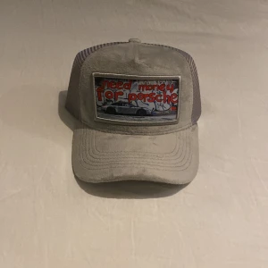 Revenite keps - En grå revenite keps som är helt ny passar vem som helst. Den har ett skönt mocka material men en snygg bild (need money for Porsche)