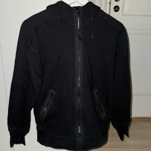 C.P. Company Goggle Zip Hoodie - Använd en fåtal gånger men fortfarande i bra jättebra skick. Säljs pga att den inte passar mig i längden längre. Köpt från FarFetch för 3400kr november 2022. 8/10 i skick! Tags finns  