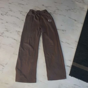 Bruna byxor från Shein - Säljer ett par bruna byxor från Shein i storlek 158. De är bekväma och har en avslappnad passform med resår i midjan. Perfekta för en chill dag hemma eller en avslappnad utflykt. Och inte mkt använda