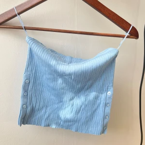 Ljusblå ribbad linnetopp - Säljer en superfin ljusblå ribbad linnetopp med smala axelband från Zara. Toppen har knappar på sidan som en snygg detalj. 