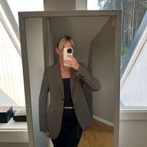 Brun kavaj - Säljer en stilren brun kavaj med en klassisk passform. Perfekt för både vardag och fest. Kavajen har långa ärmar och knäpps med en enkel knapp framtill. Den är i ett snyggt och tidlöst snitt som passar till det mesta. Perfekt för att höja din outfit till nästa nivå!