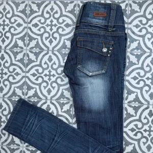 Lowwaiste jeans - Säljer dessa lowwaiste jeans från märket Miss Anna🌸 Jeansen är mörkblåa och har fina trendiga detaljer på både bakfickorna och framfickorna. De passar perfekt för dig som är lite mindre! Det finns en defekt vid en av hellorna bak (se bild)