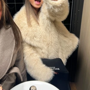 Beige pälsjacka - Säljer en supermysig beige pälsjacka som är perfekt för att hålla sig varm och stilren under kyliga dagar. Jackan har en fluffig och lyxig känsla med långa ärmar och en oversized passform. fick i födelsedagspresent men används inte💗 Den är mer beige!