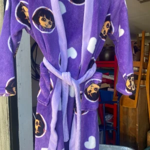 Lila morgonrock med karaktärsmotiv från Nickelodeon - Säljer en supermjuk och mysig lila morgonrock med ett gulligt karaktärsmotiv från Nickelodeon. Den har långa ärmar och ett praktiskt bälte i midjan. Perfekt för att mysa runt hemma i!