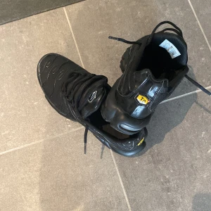 Svarta Nike sneakers - Säljer ett par svarta Nike sneakers i bra skick. De har en cool design med synlig Air-dämpning i sulan och TN-logga på baksidan. Perfekta för både vardag och träning!