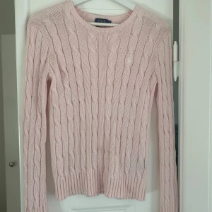 Rosa stickad tröja från Ralph Lauren - Säljer en superfin rosa stickad tröja från Ralph Lauren. Den har ett klassiskt flätmönster och är perfekt för både höst och vår. Nypris är ungefär 2000kr men jag säljer för 500kr🩷