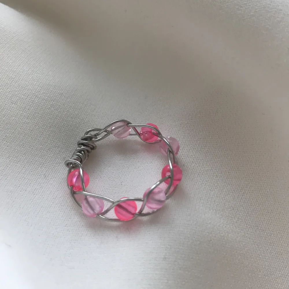 En egengjord ring av silvrig smyckestråd🥰 Den är inflätad med olika nyanserade rosa pärlor!           stl : S    Den är Nickel fri, Bly fri och Kadium fri🤩. Accessoarer.