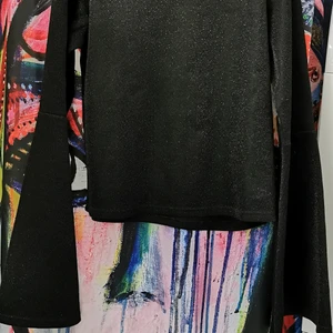 Svart glittrig topp.  - Långärmad med trumpetärm. Glittrig. Storlek S