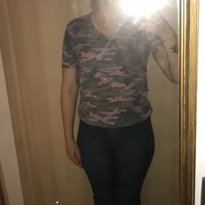 Grön-rosa kamorflage tshirt - Grön/grå/rosa camo tshirt i xs-s, mjukt tyg och sitter bra. skulle vara snyggare på någon med lite större bröst än jag, då den är väldigt figursydd! köpt på en natt-marknad i thailand för ca 3 år sedan och väl använd, men den passar inte mig längre. väl använd men den är hundra provcent hel och ren, inga hål/inget slitage